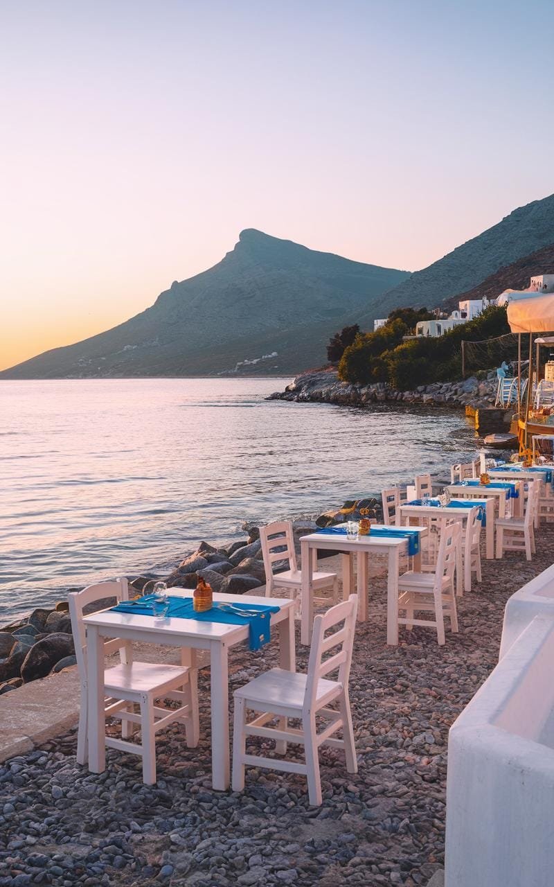 Greek seaside taverna at sunset with tables near the water and the aroma of grilled fish in the air