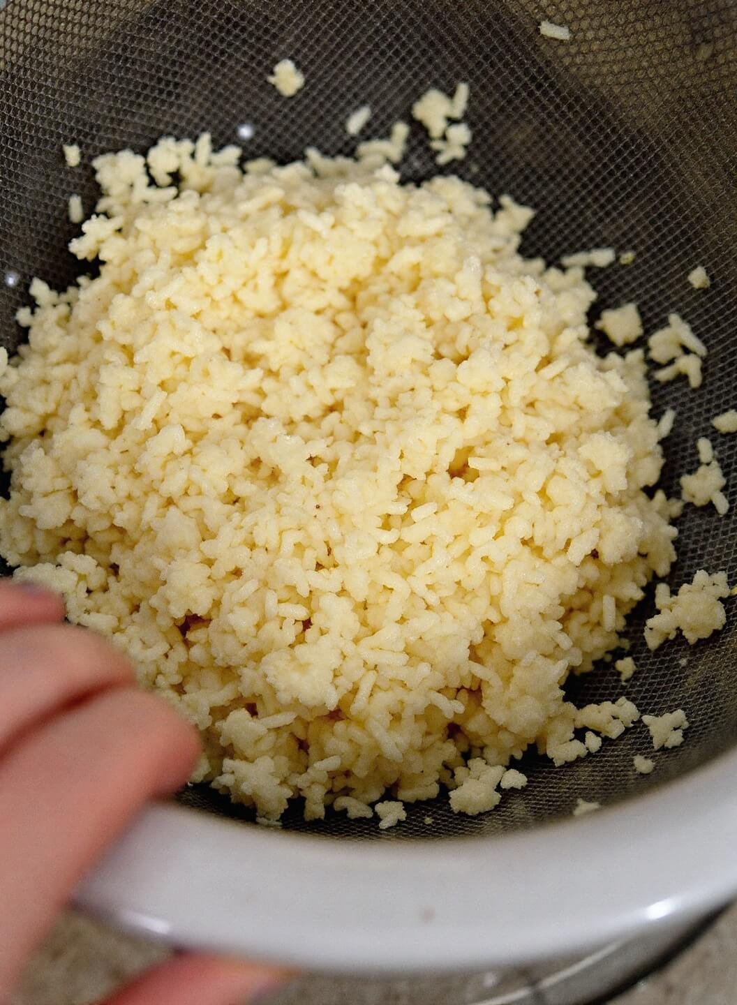 Creamy Keto Chicken Alfredo With Cauliflower Noodles 5 Steaming cauliflower rice being pressed dry in a white colander