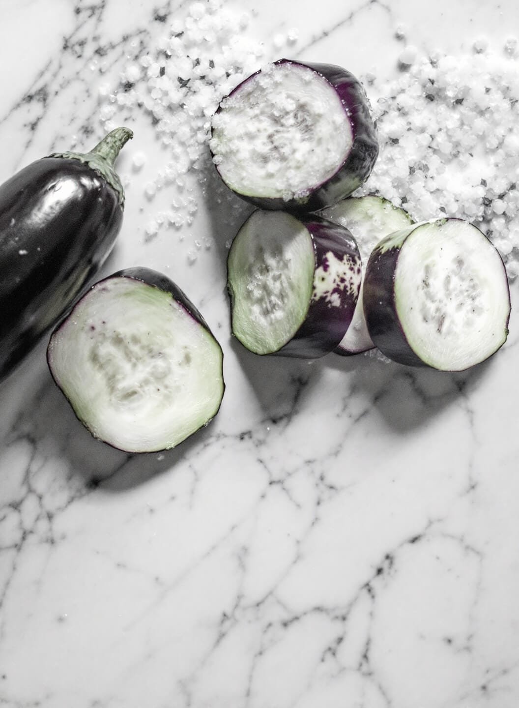 Two Easy Low-Carb Beef Lasagna Recipes: Eggplant &Amp; Cheese-Based 4 Sliced eggplant sweating out moisture with salt crystals on a marble counter.
