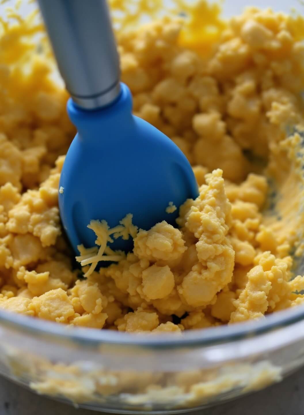 Ultimate Keto Grilled Cheese (With Chaffle Or Almond Flour Bread Options) 3 Close-up view of keto chaffle preparation including an egg and cheese mixture in a glass bowl with a whisk under bright kitchen lighting.