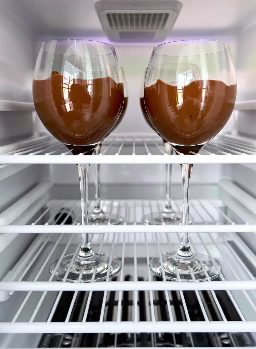 High-Protein Chocolate Mousse (Ready In 15 Minutes!) 7 Four glasses of prepared chocolate mousse aligning perfectly on a refrigerator shelf for setting