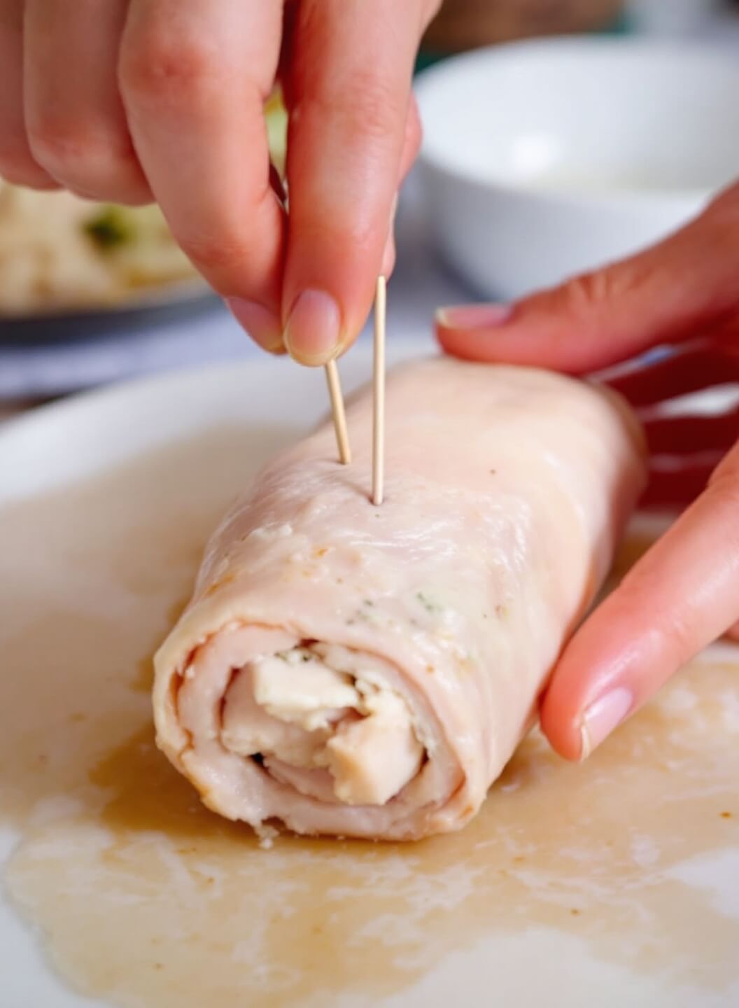 Keto Chicken Cordon Bleu 5 Hands securing a chicken cordon bleu with toothpicks for cooking