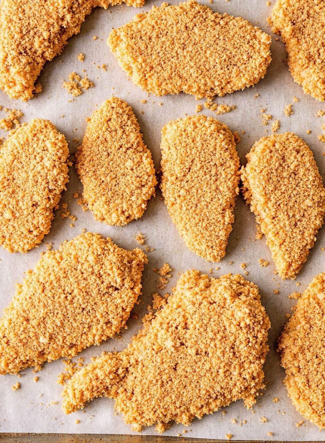 Crispy Buffalo Chicken Breast (3 Ways) 9 Golden-breaded chicken cutlets arranged evenly on a parchment-lined baking sheet ready for oven baking