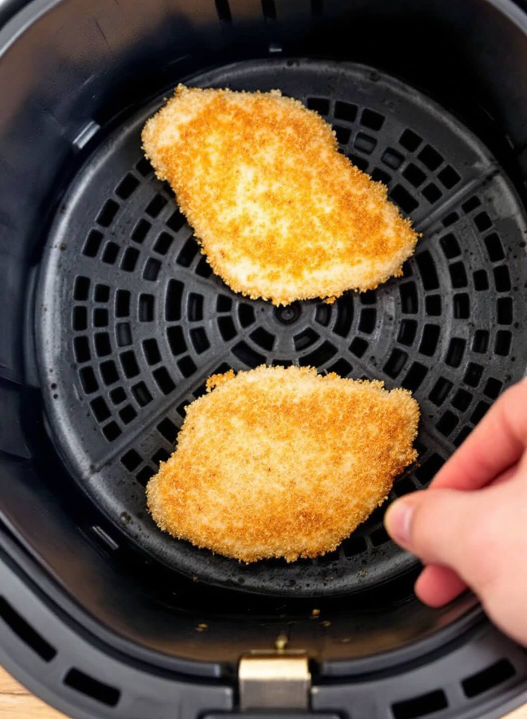 Crispy Buffalo Chicken Breast (3 Ways) 7 Breaded chicken cutlets in air fryer basket mid-cooking with golden exterior, demonstrating flipping technique