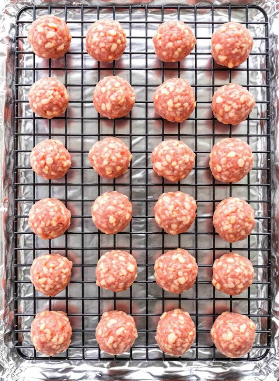 Bison Meatballs: Lean &Amp; Flavorful Italian-Style 7 Raw meatballs evenly spaced on a wire rack above a foil-lined baking sheet