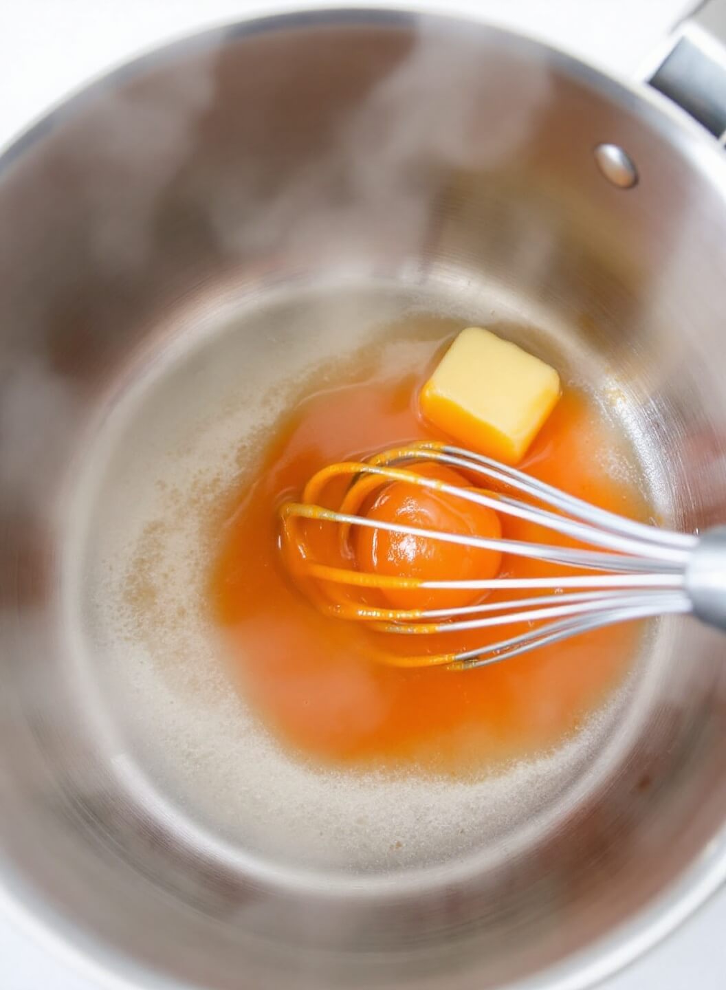 Making buffalo sauce in a stainless steel pan with melted butter and hot sauce over medium heat