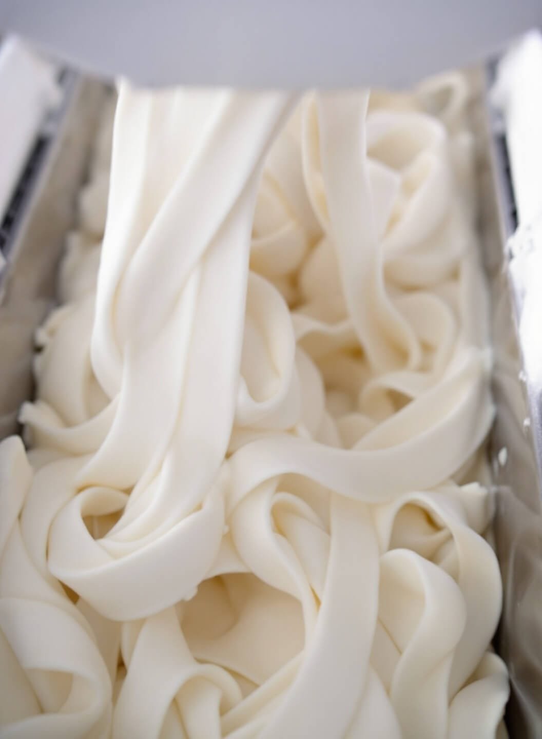 Vanilla keto ice cream being churned in a machine forming creamy ribbons.