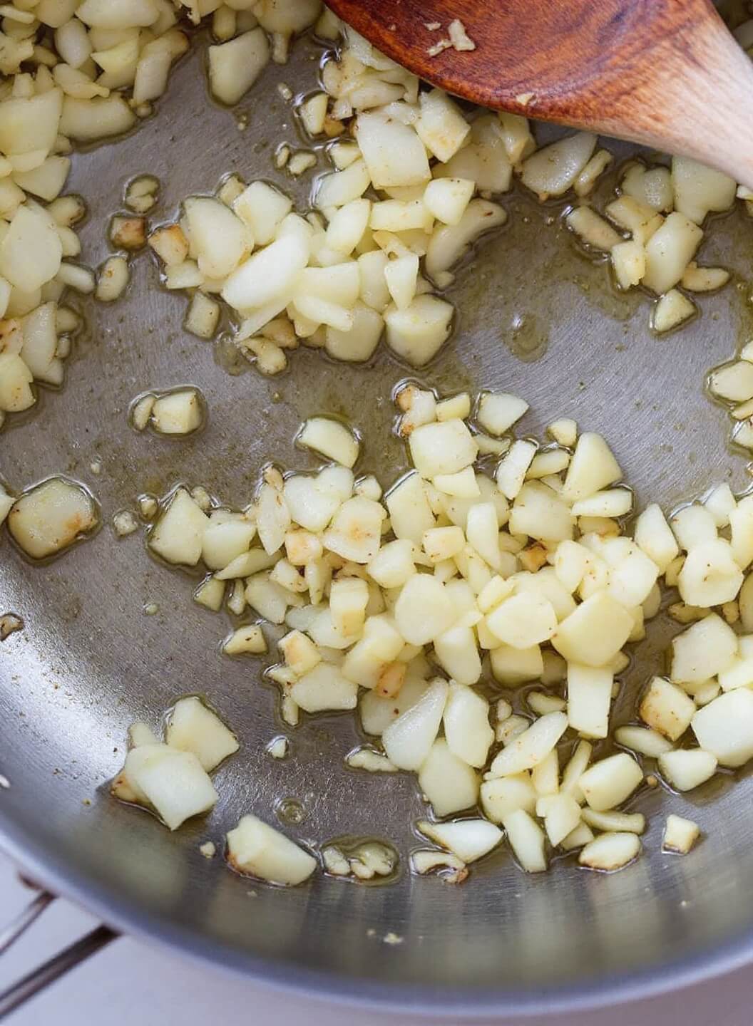 Bbq Jackfruit Pulled &Quot;Pork&Quot; (Vegan) 4 Sizzling diced onions in a stainless steel skillet with edges caramelizing, and a plate of minced garlic ready for cooking nearby