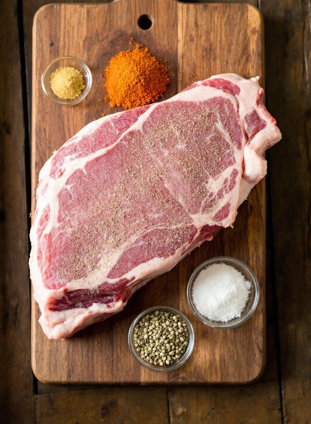 Slow-Cooked Pork Carnitas (Low-Carb) 3 Raw pork shoulder with seasoning rub and ingredients displayed on a rustic wooden board