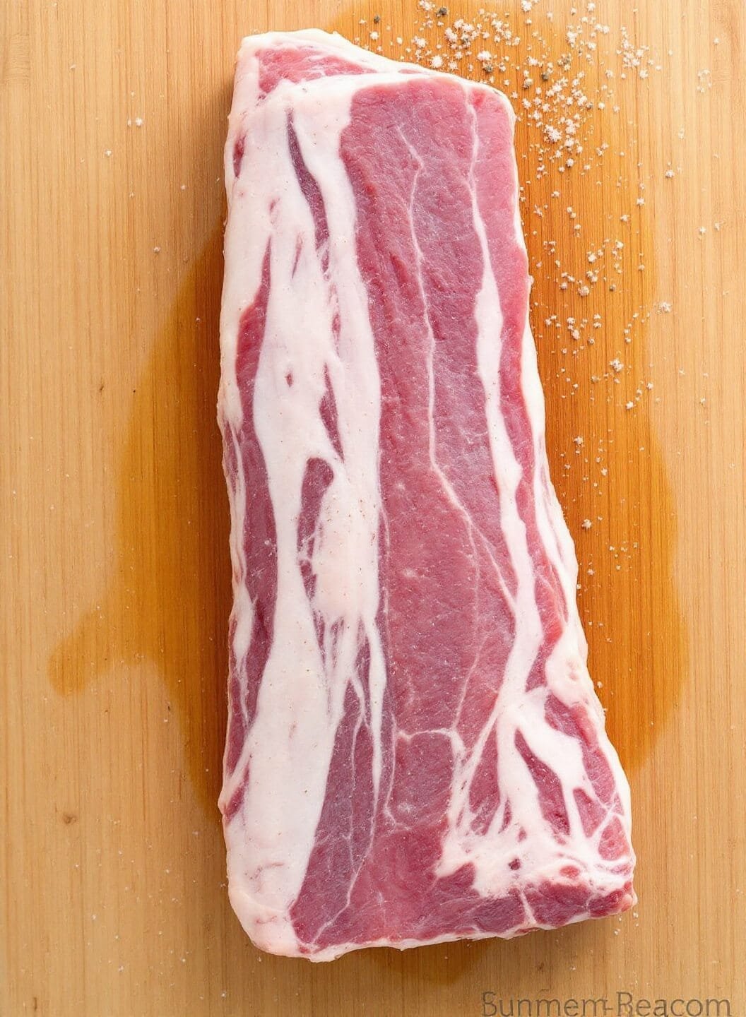Sugar-Free Spicy Korean Bbq Ribs 3 Overhead shot of fresh pork ribs on a wooden cutting board with salt and pepper for seasoning.