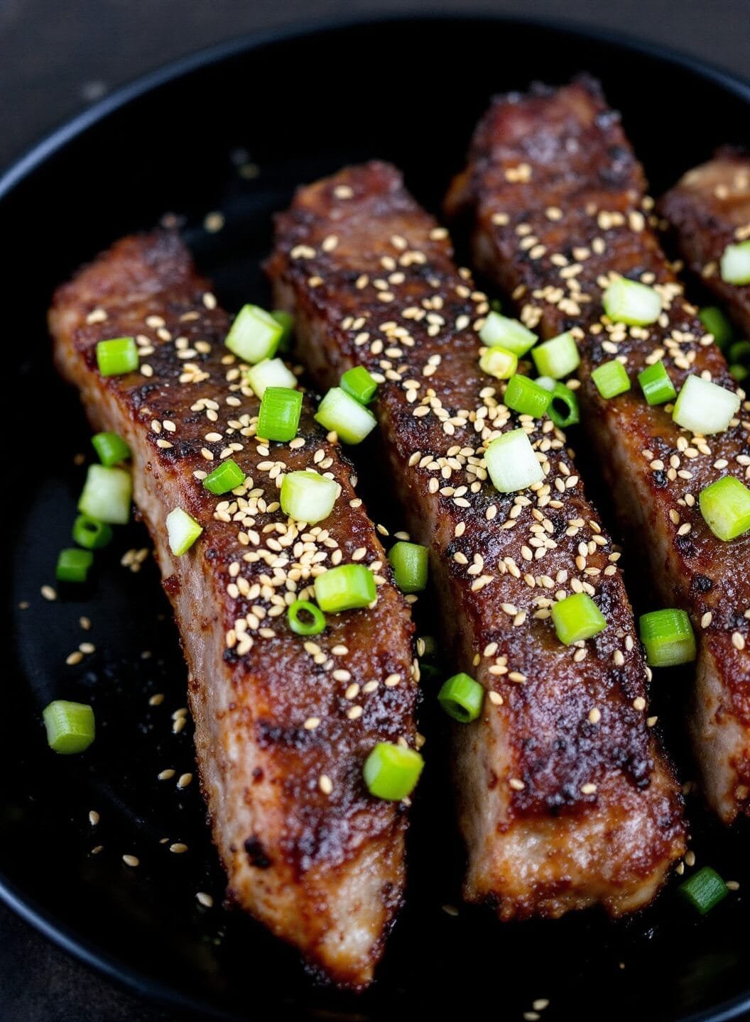 Sugar-Free Spicy Korean Bbq Ribs 7 Garnished ribs with green onions and sesame seeds served on a black ceramic plate