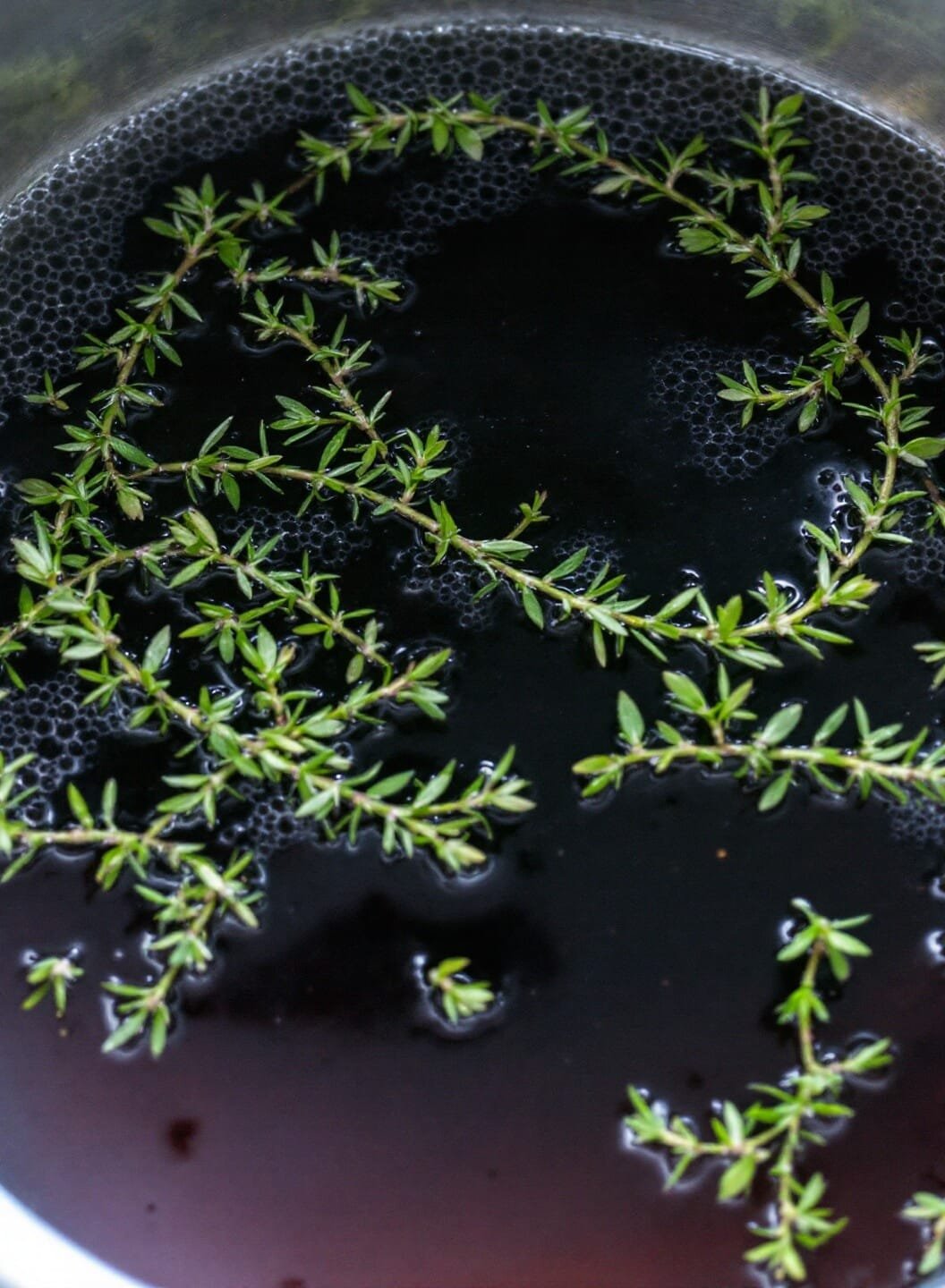 Classic French Onion Soup (Without Bread) 5 Simmering dark broth with floating thyme sprigs and a bubbling surface