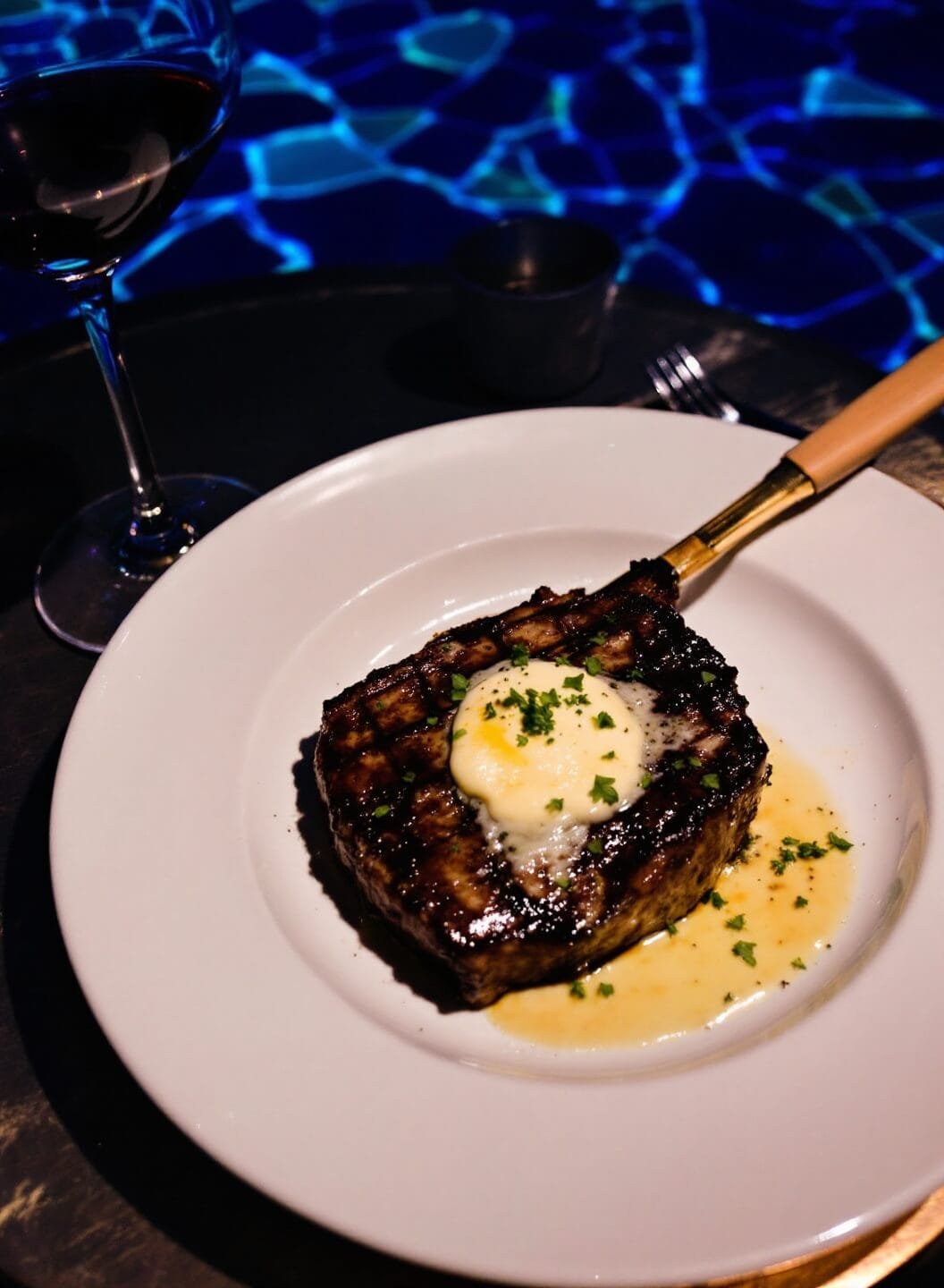 Perfect Pan-Seared Ribeye With Garlic Butter 7 Plated ribeye steak with herbs and garlic butter under dramatic lighting
