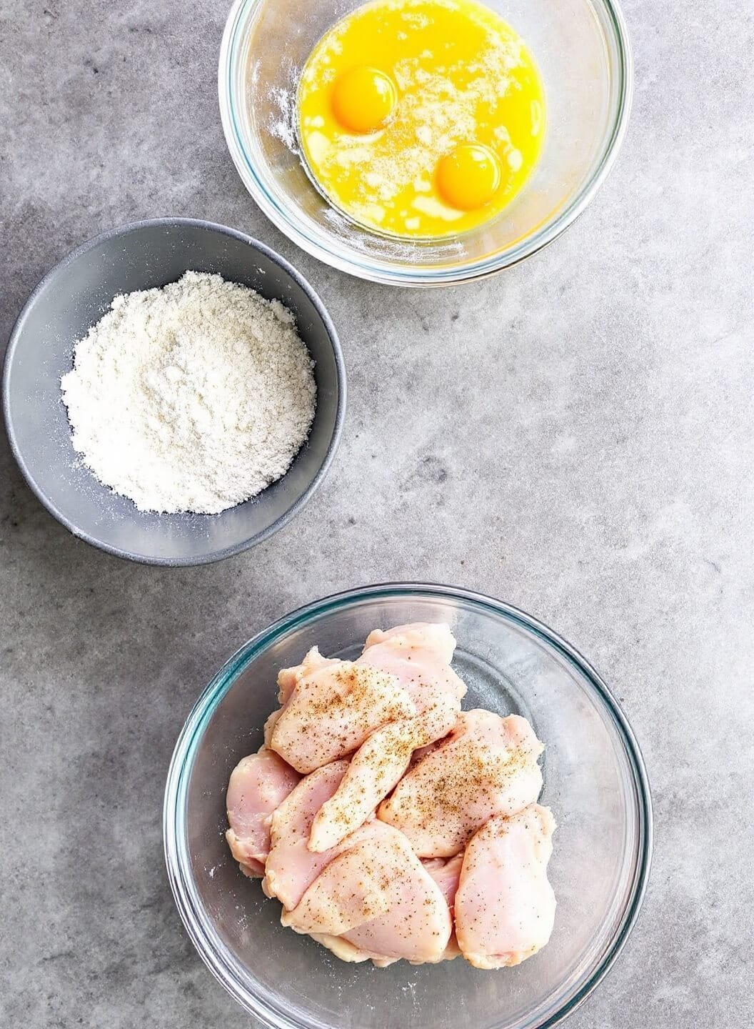 Easy Keto Chicken Parmesan With Almond Flour Breading 4 Three bowl breading station setup with beaten eggs, almond flour mixture and seasoned chicken