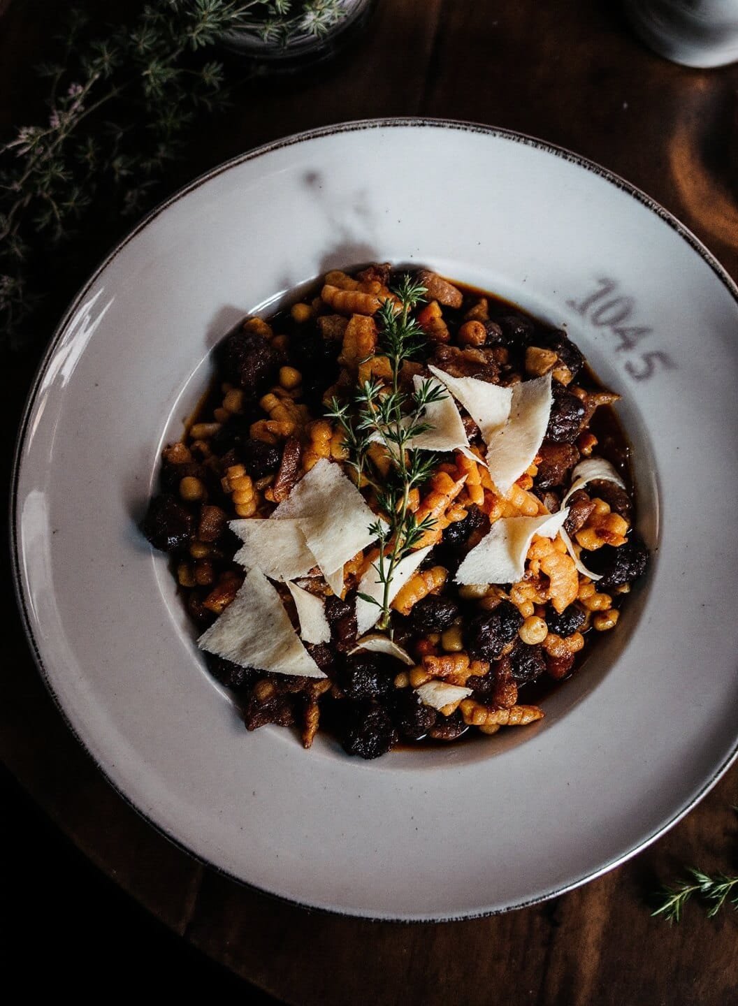 Creamy Mushroom Cauliflower Risotto 7 Plated dish with parmesan shavings and thyme sprigs on a rustic wooden table under moody lighting