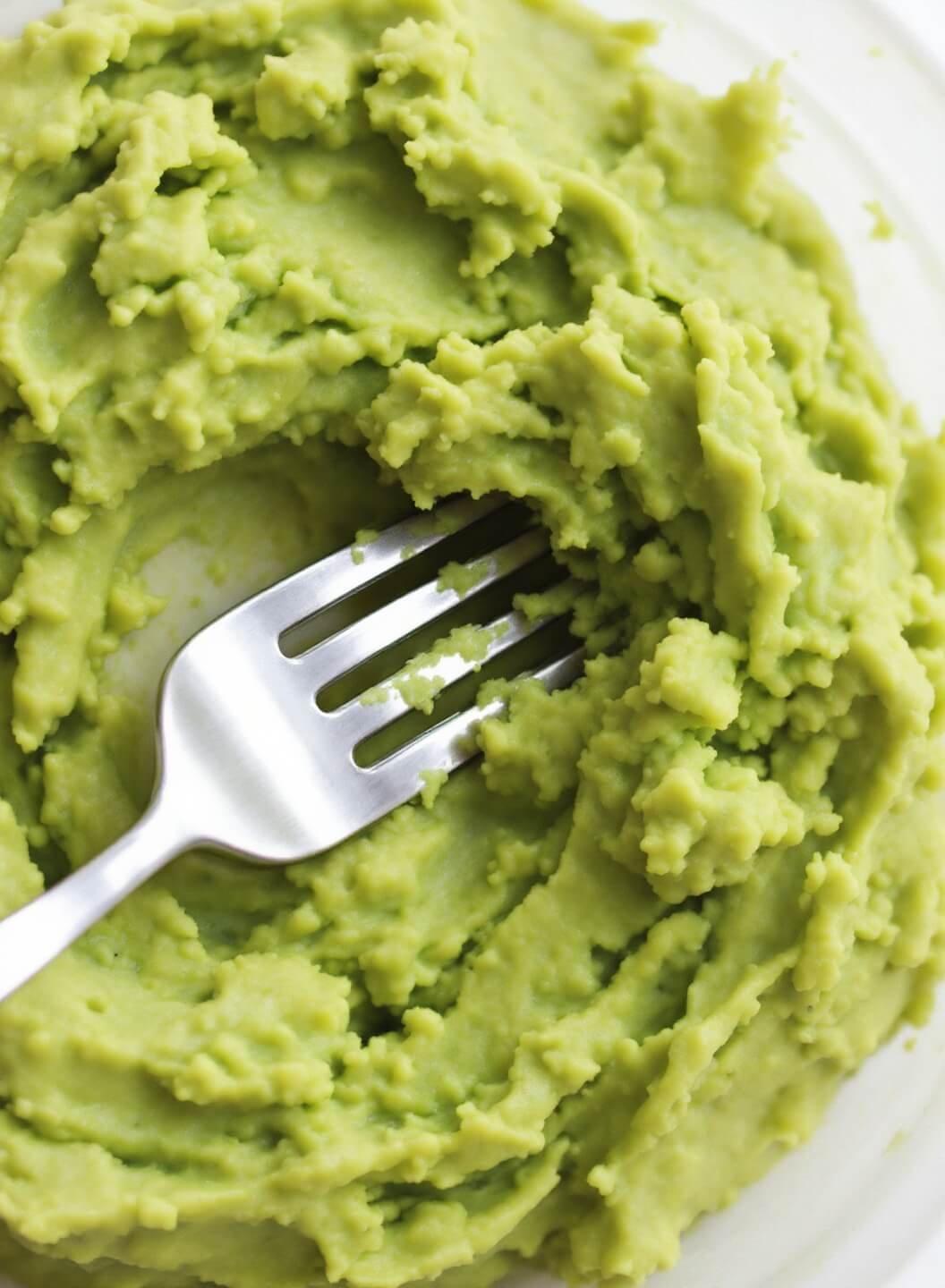 Easy Keto Guacamole (5-Minute Restaurant Style) 5 Mashing avocados with a silver fork, highlighting chunky texture under soft natural lighting