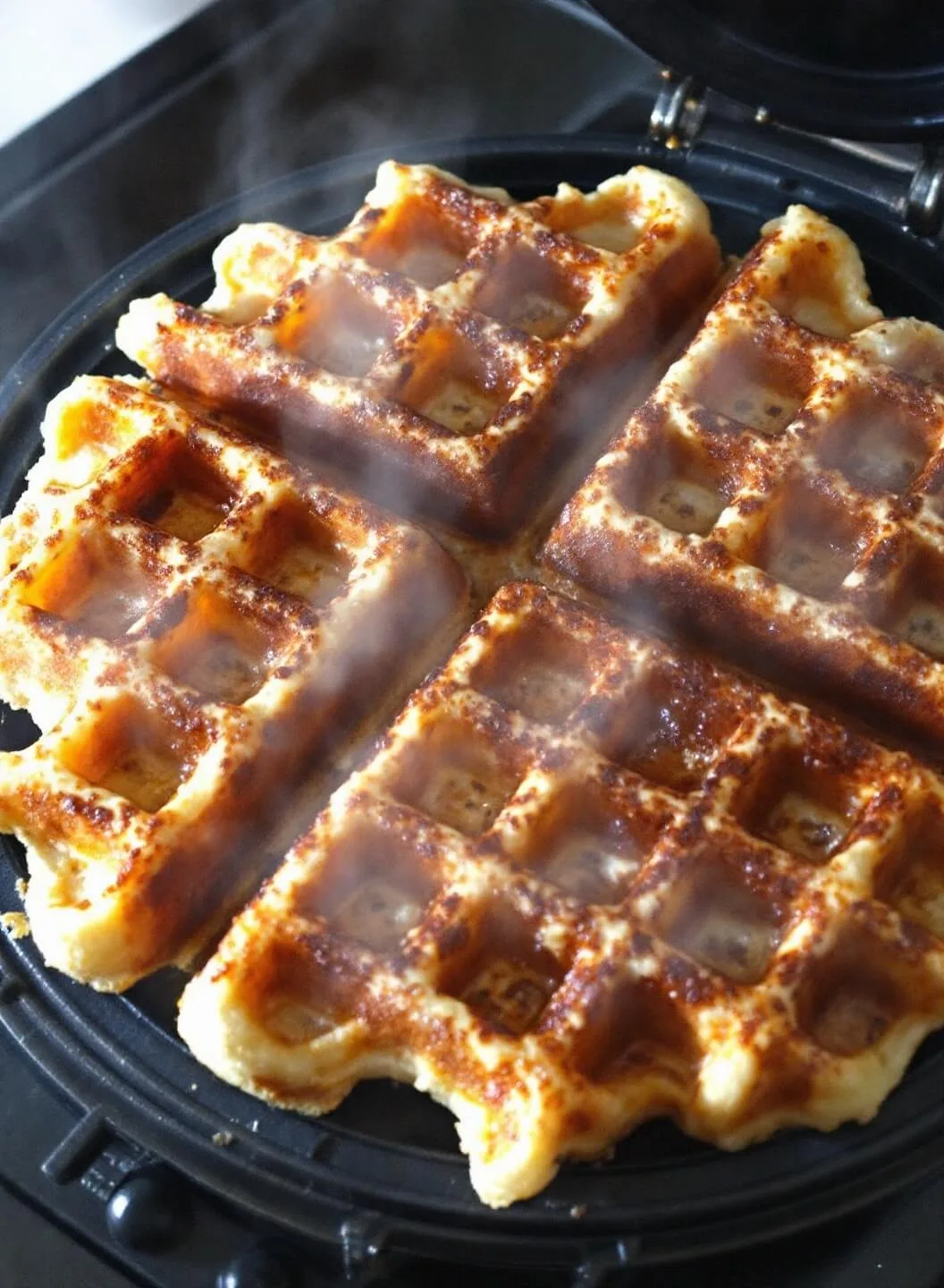 Perfectly cooked golden-brown belgian waffle with crispy squares and steam rising