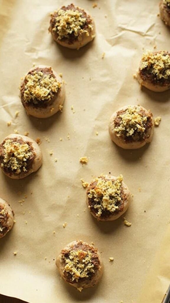 Creamy Spinach And Cheese Stuffed Mushrooms 5 Stuffed mushrooms arranged on parchment paper ready for baking